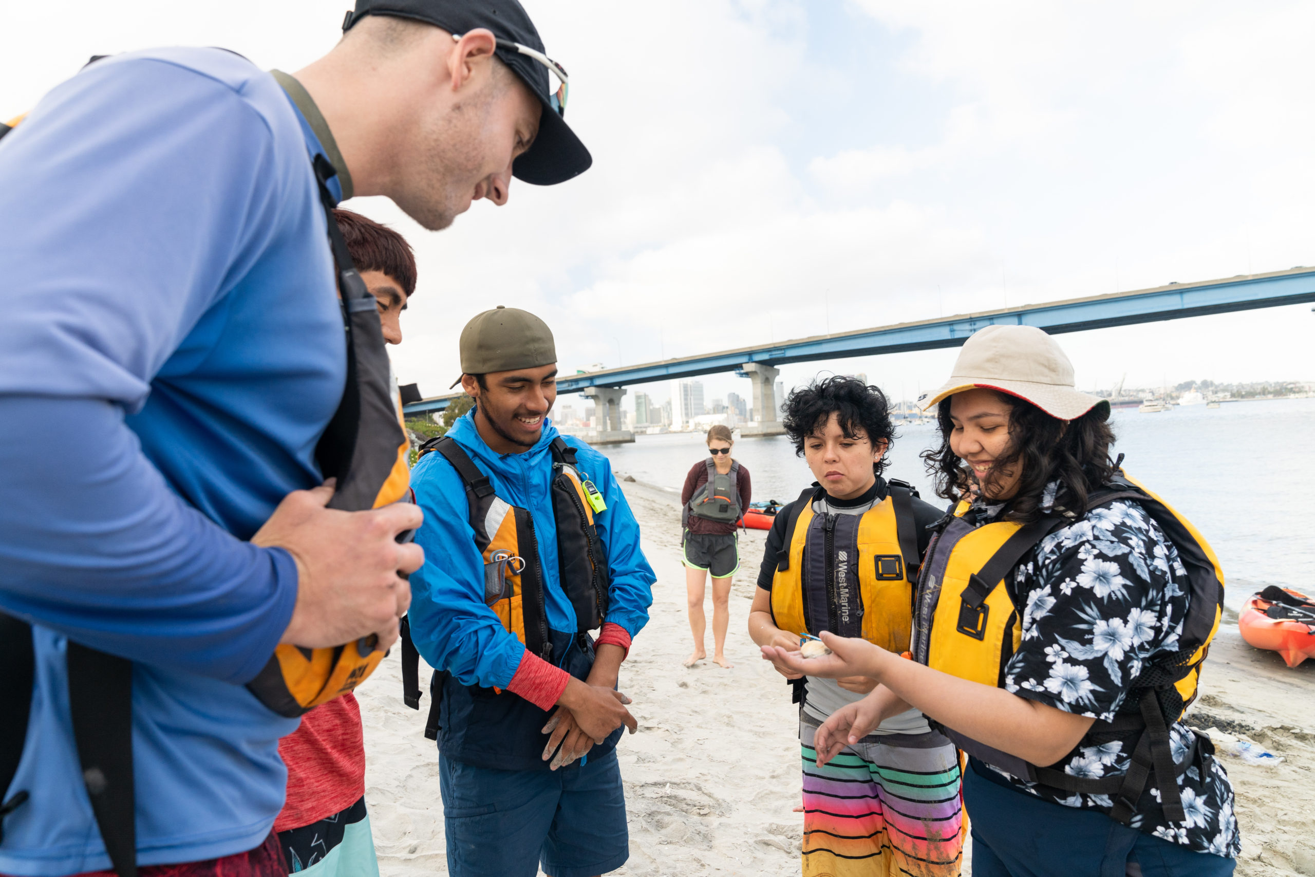 Two Outdoor Outreach youth participants showing off their seashells to Outdoor Outreach instructors. 