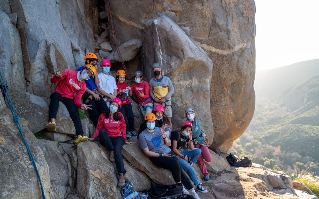 Image of Outdoor Outreach particiapnts standing together on a large rock while rock climbing.